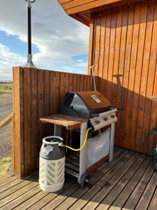 una parrilla sentada en una terraza de madera junto a una valla en Guesthouse Helluland en Þingeyjarsveit