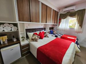 um quarto com 2 camas e um cobertor vermelho em Pousada Lugama em Bento Gonçalves
