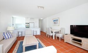 a living room with a couch and a tv and a table at Fairshore 38 Beachfront Balcony in Noosa Heads