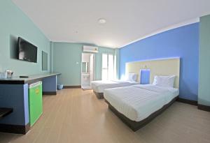 a bedroom with two beds and a blue wall at Central Park Hotel in Sing Buri