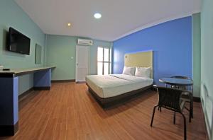 a bedroom with a bed and a table and a desk at Central Park Hotel in Sing Buri