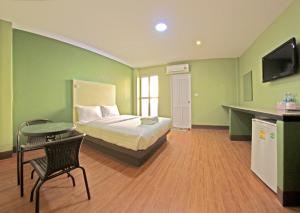 a bedroom with a bed and a table and a television at Central Park Hotel in Sing Buri