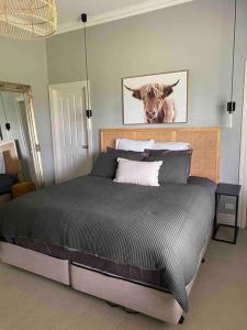 a bedroom with a bed with a cow picture on the wall at Prouts lodge in Eden Park