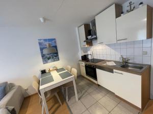 a small kitchen with a small table and a couch at Kapitänshaus W04 in Laboe