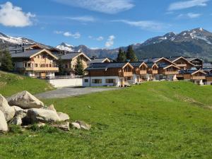 een groep huizen op een grasheuvel met bergen bij Filzstein Resort Chalet - Zillertal Arena, Hohe Tauern, Salzburgerland, Krimml, Hochkrimml in Krimml