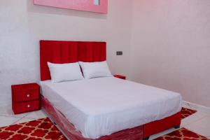 APPARTEMENT DE LUXE A LAAYOUNe في العيون: غرفة نوم بسرير كبير مع اللوح الأمامي الأحمر