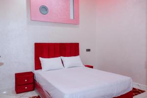 APPARTEMENT DE LUXE A LAAYOUNe في العيون: غرفة نوم بها اللوح الأمامي الأحمر وسرير أبيض