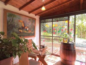 Un comedor con una mesa de cristal y un cuadro de pájaros. en Chalé de montaña con Jacuzzi, en Guarne