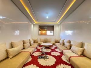 ein Wohnzimmer mit einem großen Sofa und einem roten Teppich in der Unterkunft Élégant appartement au cœur du Laâyoune in El Aaiún