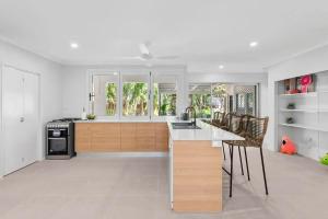 a kitchen with white walls and wooden cabinets and appliances at Belle Escapes Sandpipers Beach House in Palm Cove