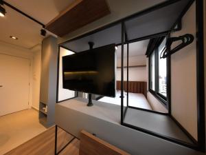Una habitación con un televisor de pantalla plana en una pared. en Studio Walk B - 807, en Curitiba