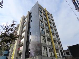 Un edificio alto con un poste amarillo encima. en Studio Walk B - 807, en Curitiba