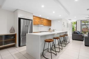 クーラムビーチにあるBelle Escapes 3 Bedroom Villa with private rooftop spaの白いキッチン(カウンター、スツール付)