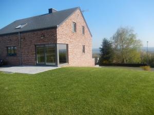 a brick building with a large lawn in front of it at Au Pré Bonheur in Houyet