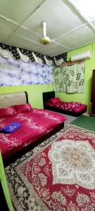 a bedroom with two beds and rugs on the floor at Nur's Homestay in Seri Manjung