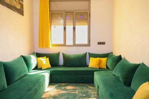 ein Wohnzimmer mit grünen Sofas und einem Fenster in der Unterkunft Bel appartement-Haut débit WIFI in El Aaiún