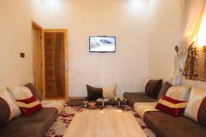 ein Wohnzimmer mit 2 Sofas und einem TV an der Wand in der Unterkunft Bel appartement-Haut débit WIFI in El Aaiún