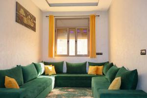 ein Wohnzimmer mit grünen Sofas und einem Fenster in der Unterkunft Bel appartement-Haut débit WIFI in El Aaiún + 2 Fotos