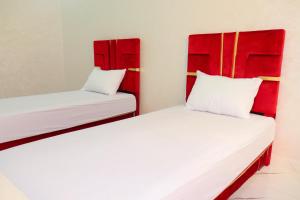 2 Betten mit roten Kopfteilen in einem Zimmer in der Unterkunft Bel appartement-Haut débit WIFI in El Aaiún