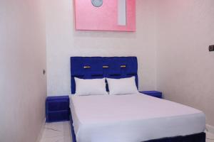 Bett mit blauem Kopfteil in einem Zimmer in der Unterkunft Bel appartement-Haut débit WIFI in El Aaiún