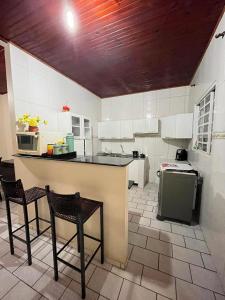 eine Küche mit einer Theke, 2 Stühlen und einem Herd in der Unterkunft Casa Lua Nova in Alto Paraíso de Goiás