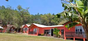 eine Reihe roter Häuser mit Bäumen im Hintergrund in der Unterkunft Cabañas Junkolal Tziscao in Santiago