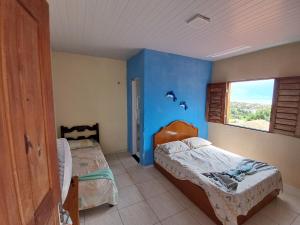 a bedroom with two beds and a blue wall at Cantinho da Tia Lucia in Beberibe