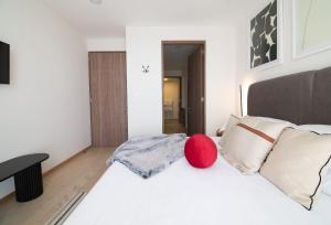 una camera da letto con un letto bianco con una palla rossa sopra di SANTA FE Red Beautiful Apartment! a Città del Messico Altre 50 foto