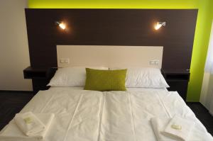 duże białe łóżko z 2 zielonymi poduszkami w obiekcie Hotel Kaskada w mieście Ledeč nad Sázavou +32 zdjęcia