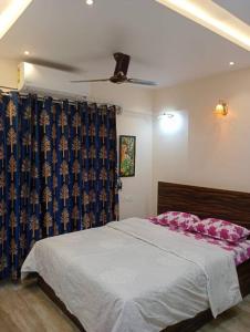 Un dormitorio con una cama y una cortina azul. en Eutopia A Zen lounge Highstreet AC Free Parking, en Pune