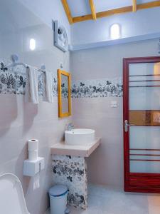 Baño blanco con lavabo y espejo en Thoddoo Haisha inn, Maldives en Thoddoo