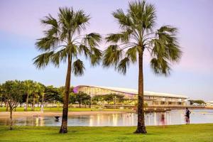 two palm trees in a park next to a body of water at Welcome Homestay Waterfront in Darwin