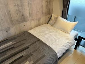 熊本的住宿－リブレ in Kumamoto 302，一张位于有墙板的房间的床位