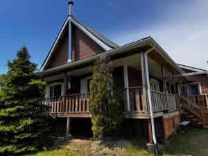a large house with a porch and a tree at Le Chadou in Tadoussac +6 photos