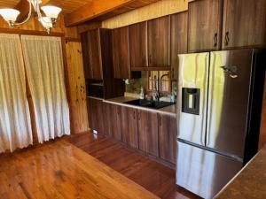 a kitchen with a stainless steel refrigerator and wooden cabinets at Le Chadou in Tadoussac