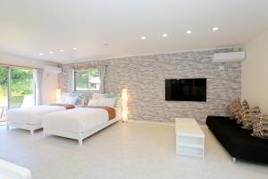 - une chambre avec 2 lits et une télévision sur un mur en briques dans l'établissement スターダストヴィラミルキーウェイ, à Fukai