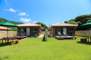 une maison avec une cour dotée de bancs et de parasols dans l'établissement スターダストヴィラミルキーウェイ, à Fukai