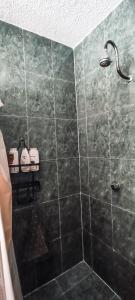 y baño con ducha y pared de azulejos negros. en Habitación con baño privado B, Centro de Coyoacán en Ciudad de México