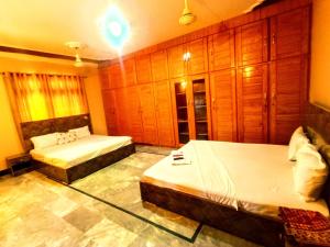 RoyalVilla Guest House Karachi في كراتشي: سريرين في غرفة بجدران خشبية