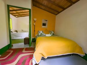 a bedroom with a yellow bed and a tub at Kantarrana Casa de Campo in Jardin