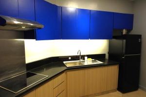 La cuisine est équipée de placards bleus, d'un évier et d'un réfrigérateur. dans l'établissement The Linden Suites, à Manille