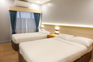 a hotel room with two beds and a window at The Linden Suites in Manila