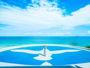 a woman standing on top of a pool overlooking the ocean at Shimoda Prince Hotel in Shimoda