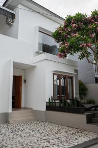 a white house with chairs and a tree with pink flowers at Terrace Mumbul in Nusa Dua