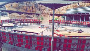 une terrasse avec des tables, des bancs et un parasol dans l'établissement Desert stars, à Wadi Rum