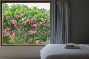 a bedroom with a window with a tree with pink flowers at Terrace Mumbul in Nusa Dua +15 photos