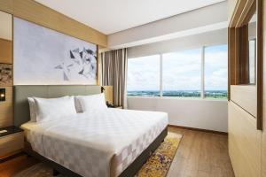 a hotel room with a bed and a window at Swiss-Belinn Modern Cikande in Serang