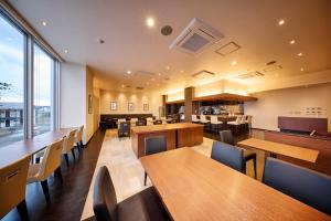 a restaurant with wooden tables and chairs and a large window at Sunnemu Hotel in Honjo in Yurihonjo