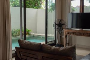 a living room with a television and a swimming pool at Terrace Mumbul in Nusa Dua