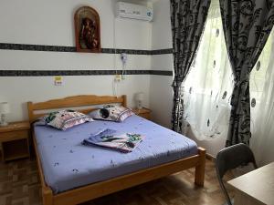 a bedroom with a bed with blue sheets and a window at Vila MariCris in Tuzla